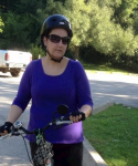 women with purple shirt standing beside a bike