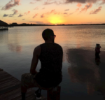 man sitting at a dock looking at sunset