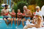 Generational family eating watermelon by a pool