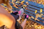 tying up shoe lace on a park bench in autumn