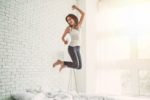 woman jumping on her bed