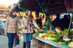 2 woman at farmer's market looking at vegetables
