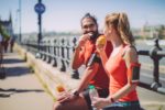 a man and woman eating oranges after a workout outside